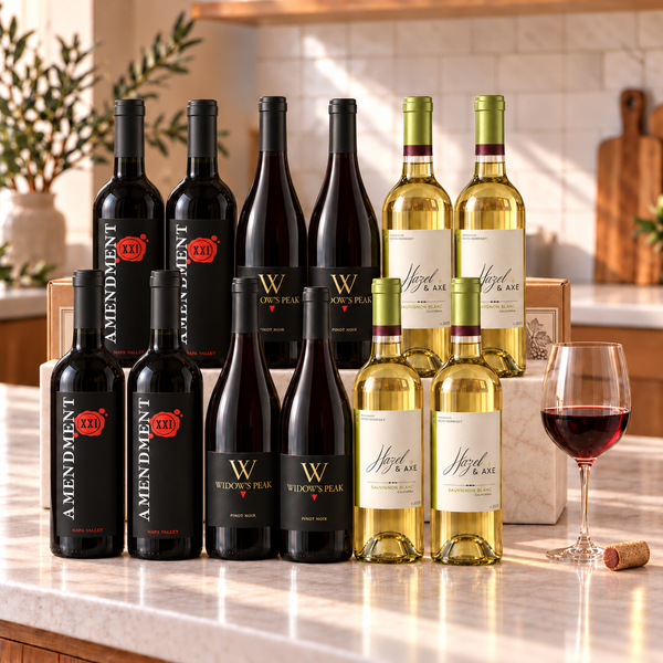 Illustrative 12-bottle mixed red and white wine selection on marble with Wine of the Month Club branded shipping box behind the bottles