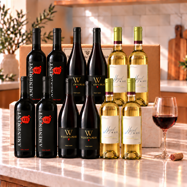 Illustrative twelve-bottle mixed red and white wine selection on a marble platform with a matching Wine of the Month Club shipping box
