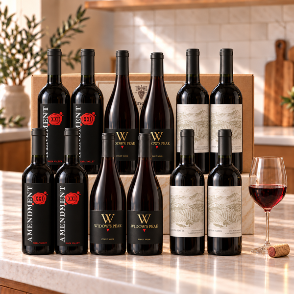 Illustrative 12-bottle red wine selection on marble with Wine of the Month Club branded shipping box behind the bottles
