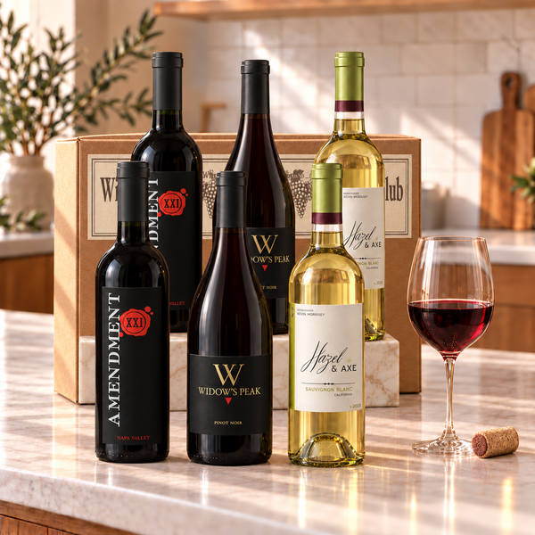 Illustrative 6-bottle mixed red and white wine selection on marble with Wine of the Month Club branded shipping box behind the bottles